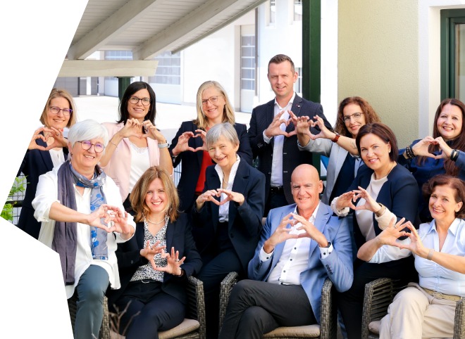 Das Team der TRAIN GmbH im Jubiläumsjahr 2024. Gruppenbild der TRAIN GmbH, auf dem alle mit den Händen ein Herz formen