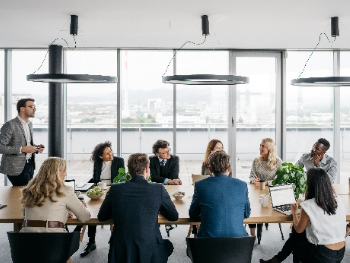Gruppenveranstaltung beim Gruppenoutplacement Ein Mann spricht vor einer Seminargruppe in modernem Ambiente.