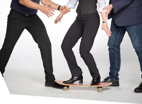 Inhaltsbild: Zwei Männer stützen eine Frau, die auf einem Skateboard steht